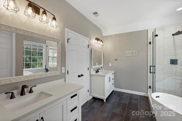 bathroom featuring a shower stall, a freestanding bath, visible vents, and a sink