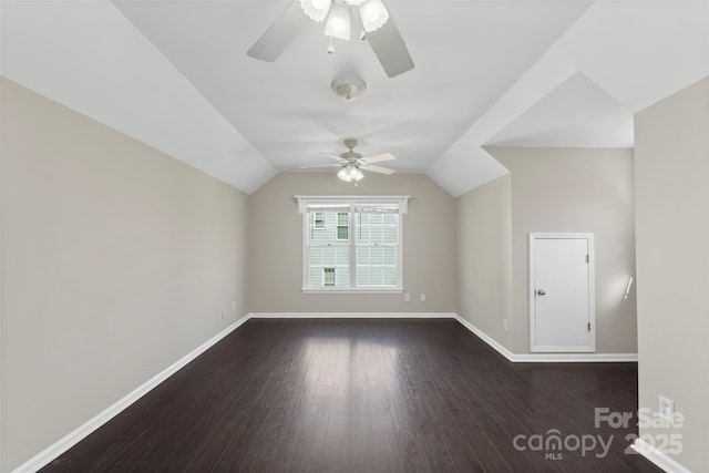 bonus room featuring lofted ceiling, dark wood finished floors, a ceiling fan, and baseboards