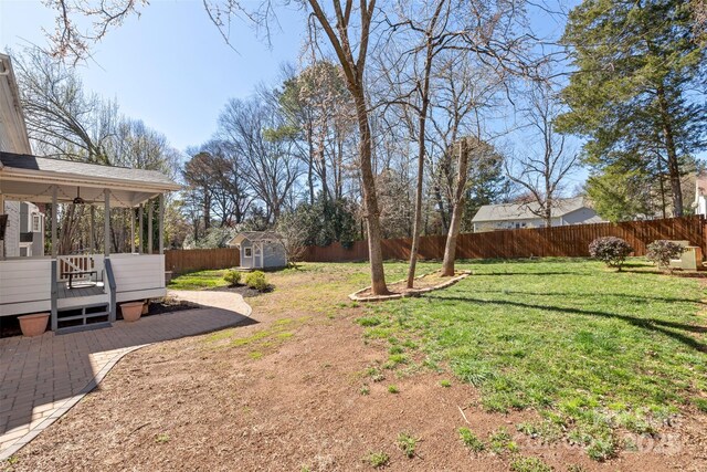 view of yard with an outbuilding, a patio, a shed, a fenced backyard, and a wooden deck