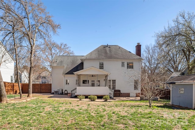 rear view of house with ceiling fan, a patio, a fenced backyard, an outdoor structure, and a lawn