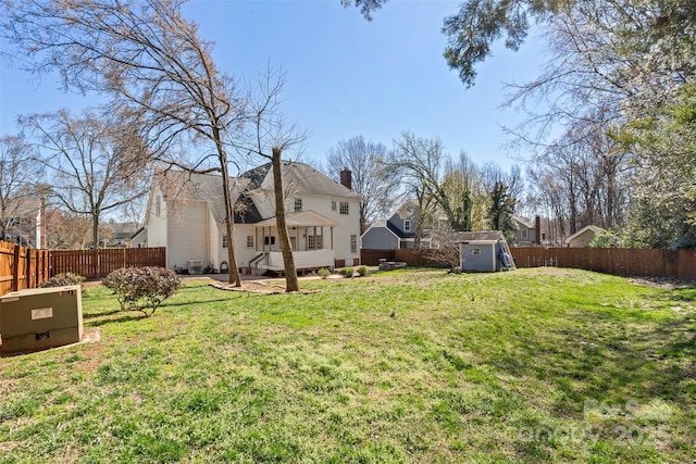 view of yard featuring an outbuilding, a storage shed, a fenced backyard, and a wooden deck