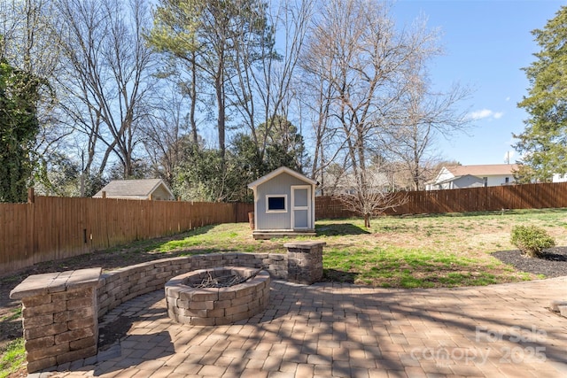 view of patio / terrace featuring an outbuilding, a fenced backyard, a fire pit, and a shed