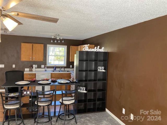 kitchen with a textured ceiling, dishwasher, sink, and ceiling fan