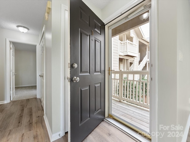 doorway featuring light hardwood / wood-style floors and a textured ceiling