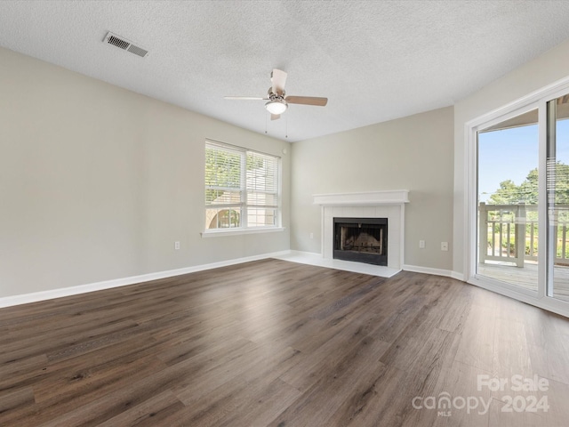 unfurnished living room featuring ceiling fan, a textured ceiling, a fireplace, and dark hardwood / wood-style flooring