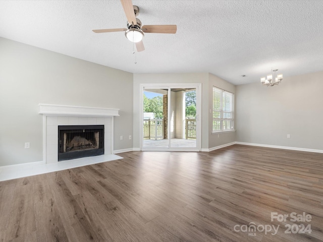 unfurnished living room with a fireplace, ceiling fan, dark hardwood / wood-style floors, and a textured ceiling