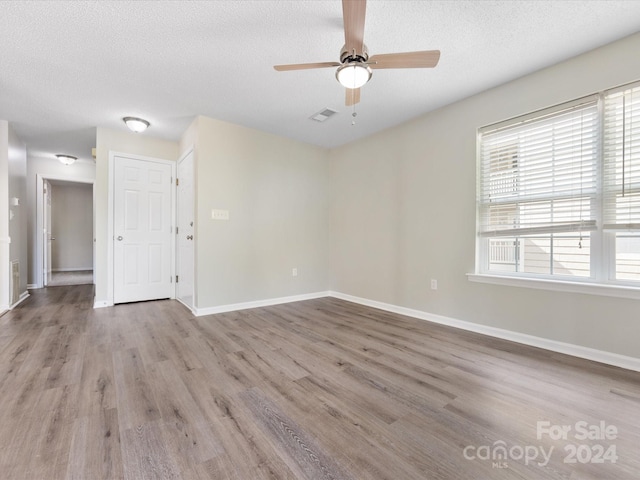 spare room with ceiling fan, a textured ceiling, and light hardwood / wood-style flooring