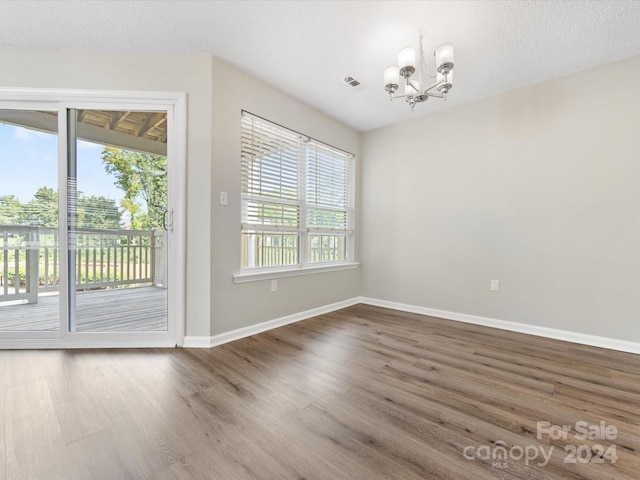 unfurnished dining area with hardwood / wood-style floors, an inviting chandelier, and a textured ceiling