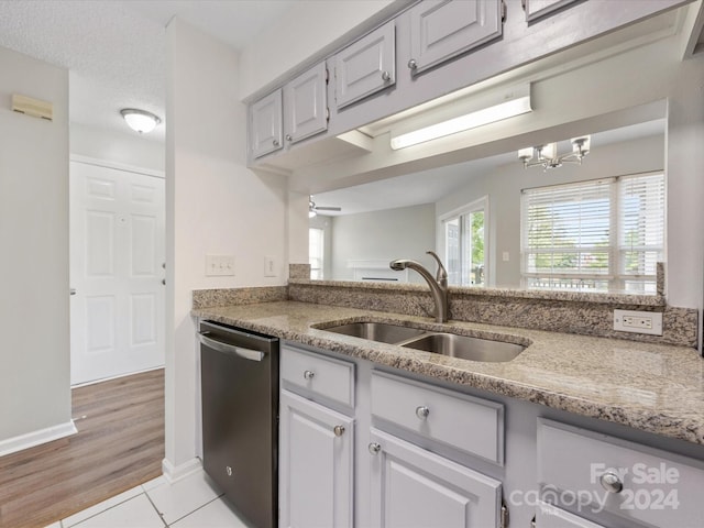 kitchen featuring light hardwood / wood-style floors, a chandelier, sink, stainless steel dishwasher, and a textured ceiling