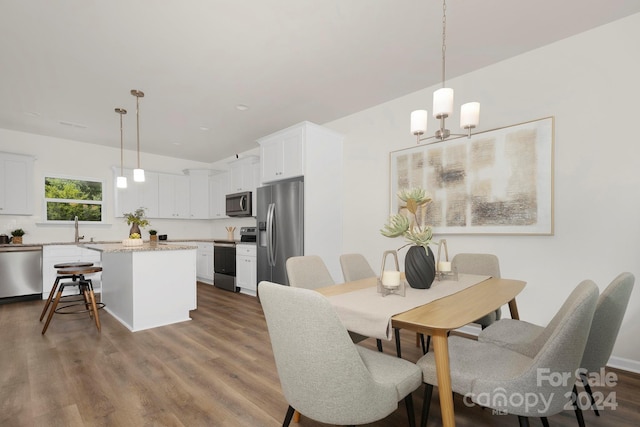 dining area featuring a notable chandelier, sink, and wood-type flooring