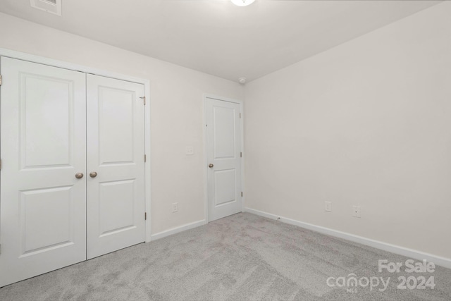 unfurnished bedroom featuring light colored carpet and a closet