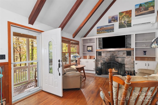 living room with a fireplace, a wall unit AC, beamed ceiling, and wood-type flooring