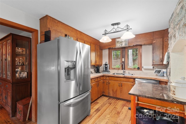 kitchen featuring sink, decorative light fixtures, light hardwood / wood-style flooring, and stainless steel appliances