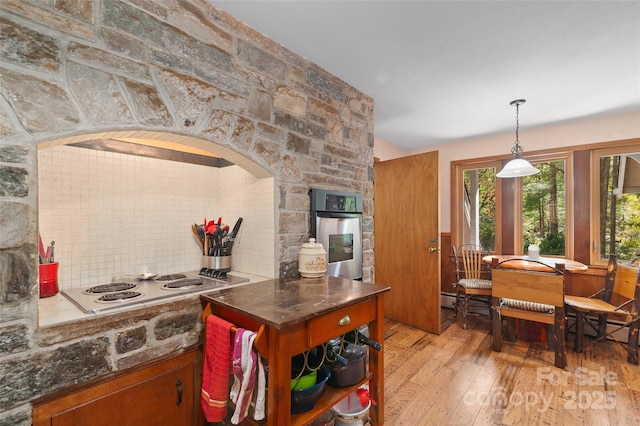 kitchen with tasteful backsplash, light wood-type flooring, stainless steel oven, and white electric stovetop