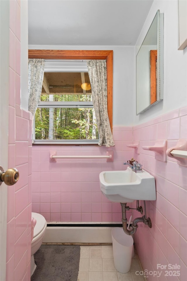 bathroom featuring tile walls, a baseboard heating unit, sink, and toilet