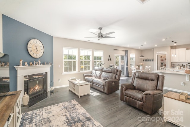 living room featuring ceiling fan, dark hardwood / wood-style flooring, and a healthy amount of sunlight