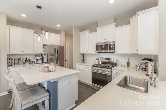 kitchen with appliances with stainless steel finishes, white cabinetry, decorative light fixtures, and sink