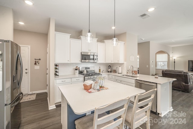 kitchen featuring dark wood-type flooring, sink, pendant lighting, kitchen peninsula, and appliances with stainless steel finishes