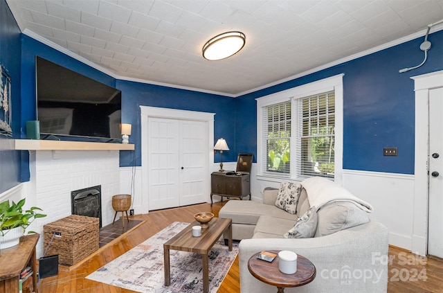 living room featuring hardwood / wood-style flooring, ornamental molding, and a brick fireplace