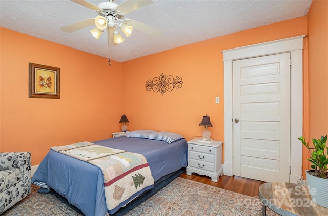 bedroom with a textured ceiling, hardwood / wood-style flooring, and ceiling fan