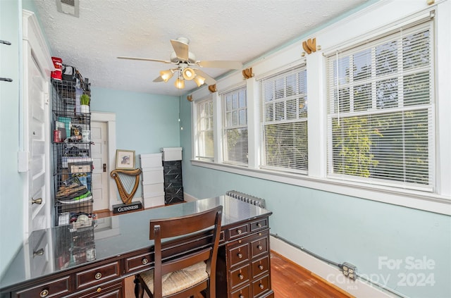 home office with hardwood / wood-style floors, a healthy amount of sunlight, a textured ceiling, and ceiling fan