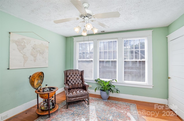 sitting room with ceiling fan, a textured ceiling, a wealth of natural light, and hardwood / wood-style floors