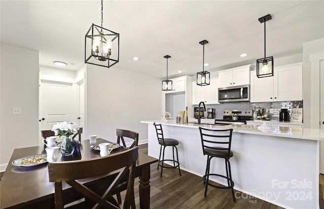 kitchen with dark wood-type flooring, appliances with stainless steel finishes, pendant lighting, and white cabinetry