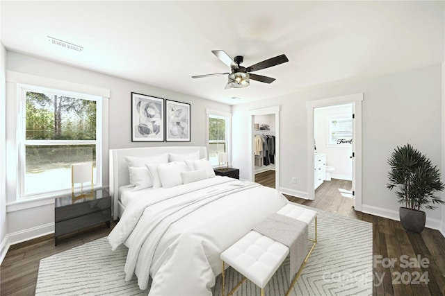 bedroom featuring connected bathroom, a closet, a spacious closet, ceiling fan, and dark hardwood / wood-style flooring