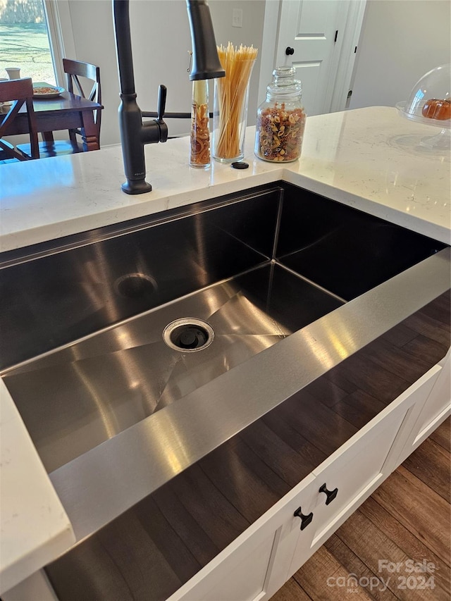 interior details featuring white cabinetry, wood-type flooring, and sink