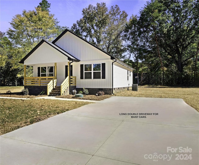 view of front of property with covered porch, a front lawn, and central AC unit