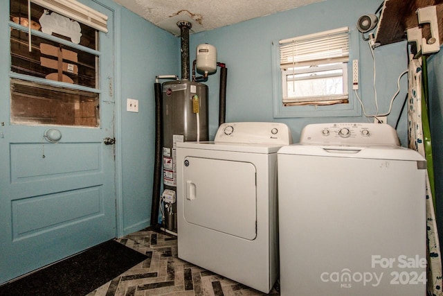 clothes washing area with water heater, independent washer and dryer, and a textured ceiling