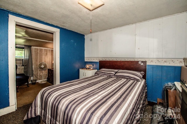 carpeted bedroom with wooden walls and a textured ceiling