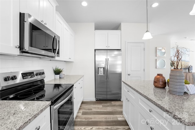 kitchen with dark wood-type flooring, white cabinets, appliances with stainless steel finishes, and decorative light fixtures