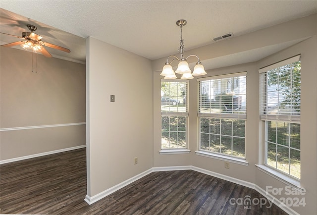 unfurnished dining area featuring ceiling fan with notable chandelier, dark wood-type flooring, and a wealth of natural light