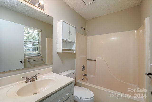 full bathroom featuring vanity, a textured ceiling, toilet, and shower / washtub combination