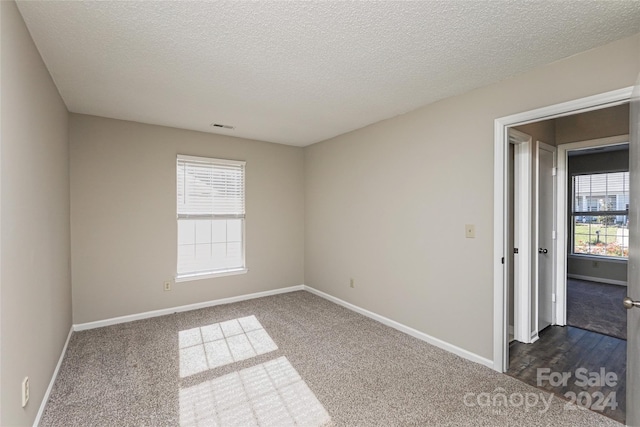 carpeted spare room featuring a textured ceiling