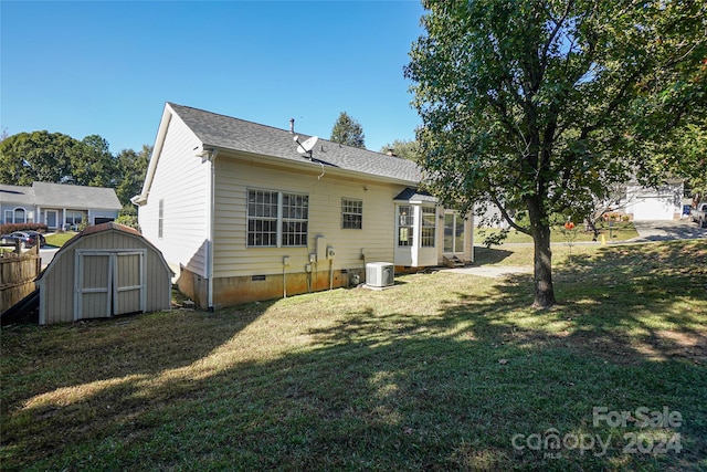 back of house featuring central AC unit, a lawn, and a storage unit