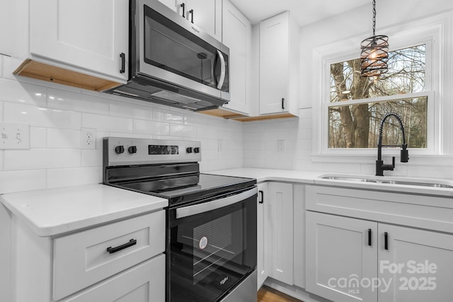 kitchen with pendant lighting, sink, white cabinetry, stainless steel appliances, and decorative backsplash