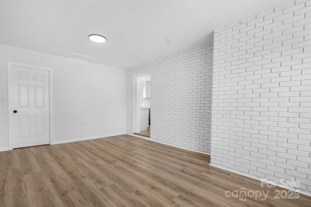 spare room with wood-type flooring and brick wall