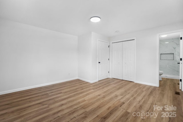 unfurnished bedroom with ensuite bath and hardwood / wood-style floors