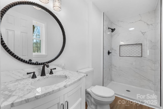 bathroom with tiled shower, vanity, and toilet