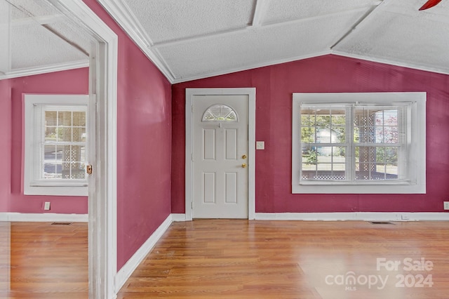 foyer featuring vaulted ceiling, light hardwood / wood-style floors, and a textured ceiling