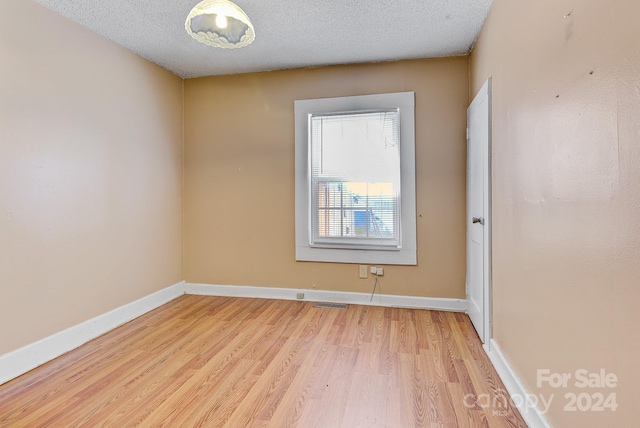 spare room with a textured ceiling and light hardwood / wood-style flooring