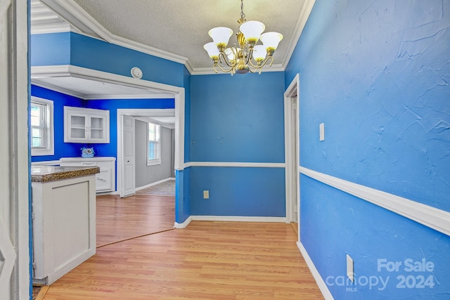 unfurnished dining area with an inviting chandelier, light hardwood / wood-style floors, ornamental molding, and a healthy amount of sunlight