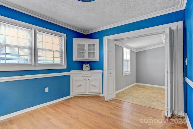 interior space with a textured ceiling, crown molding, and light hardwood / wood-style floors