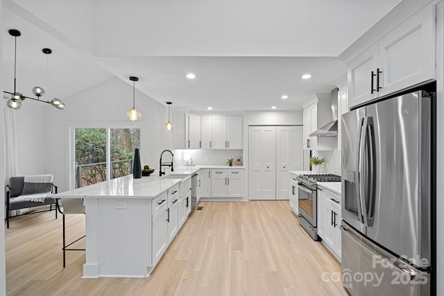 kitchen featuring stainless steel appliances, pendant lighting, decorative backsplash, white cabinetry, and wall chimney range hood