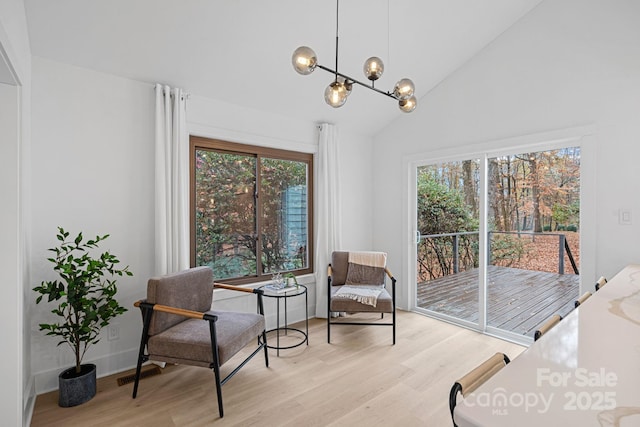 living area with high vaulted ceiling, light hardwood / wood-style floors, and a notable chandelier