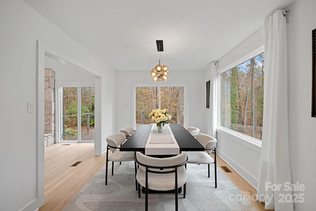 dining area with light hardwood / wood-style flooring and a chandelier