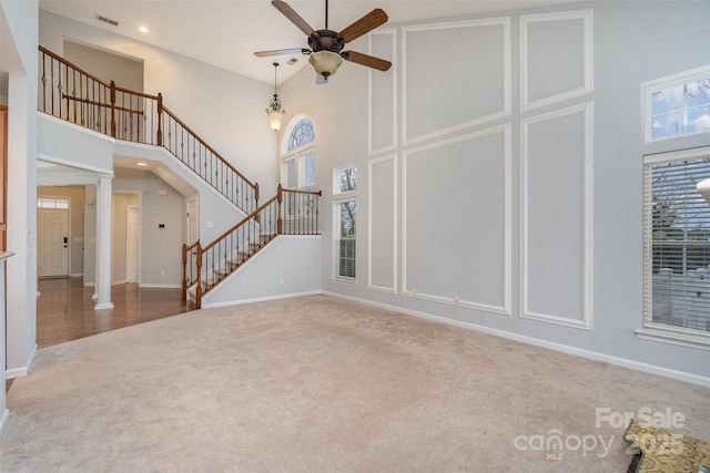 unfurnished living room featuring ornate columns, visible vents, stairway, and carpet flooring