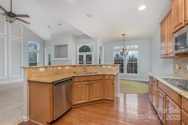 kitchen with decorative light fixtures, decorative backsplash, appliances with stainless steel finishes, a kitchen island with sink, and a sink